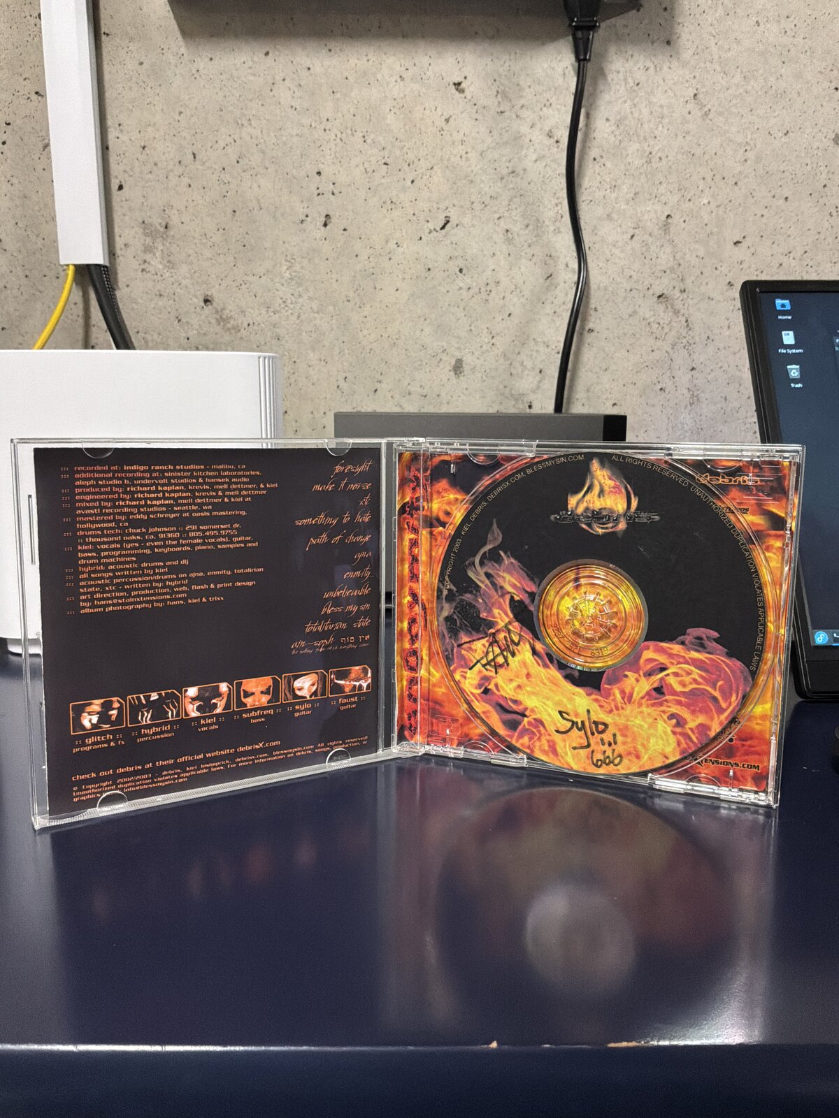 Anonymity by Debris — open case showing the liner notes and the disc, autographed by two band members